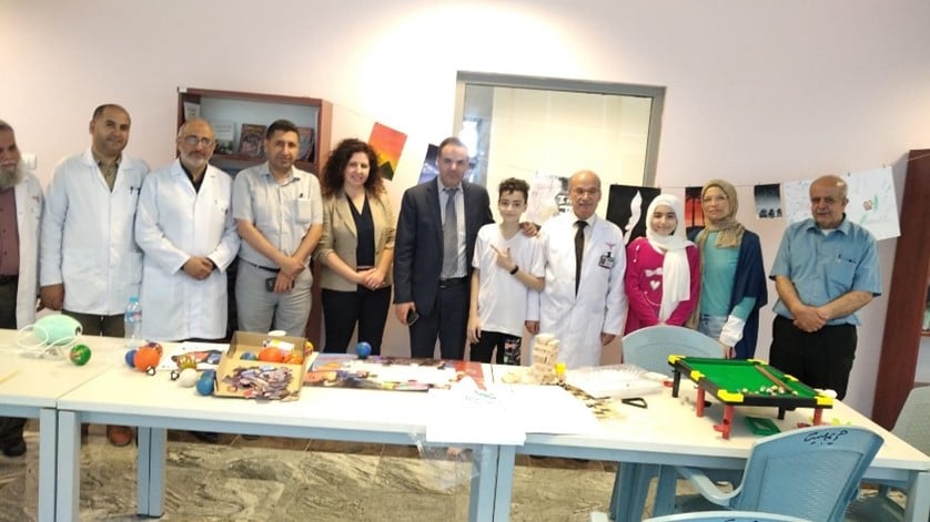 a group photo of 10 adults and 1 child standing behind a table