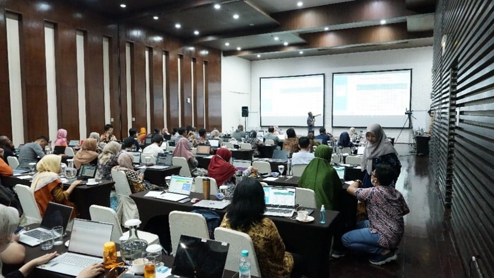 Participants of training in a meeting room, looking at the projector screen.